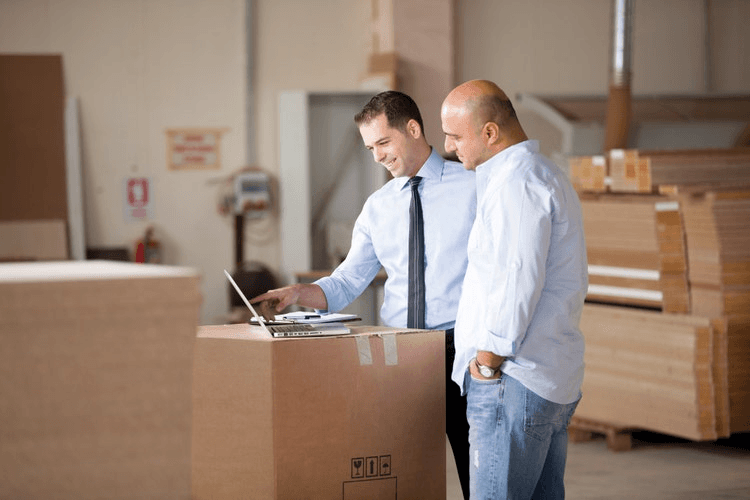 Two colleagues reviewing supplier paperwork at a screen