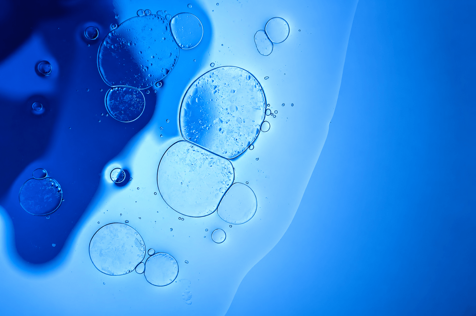 Oil and water separating into blue and pale bubbles under magnification