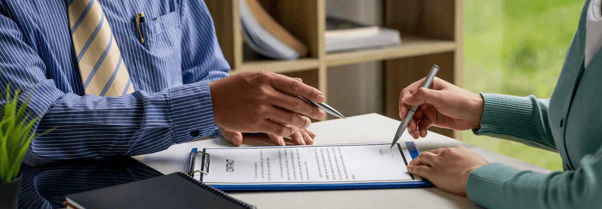 An agreement being signed across a desk, pens over a clipboard
